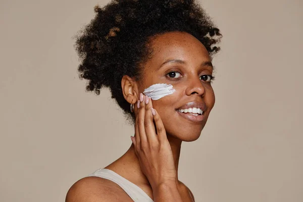 Ung svart kvinna tillämpa ansiktskräm — Stockfoto