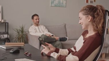 Kafkasyalı genç bir çiftin akıllı telefondaki teslimat uygulamasını kullanarak internetten yemek sipariş ederken orta yavaş çekimleri.