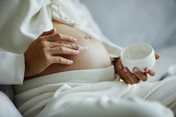 Těhotná žena nanášení krém na břicho — Stock fotografie