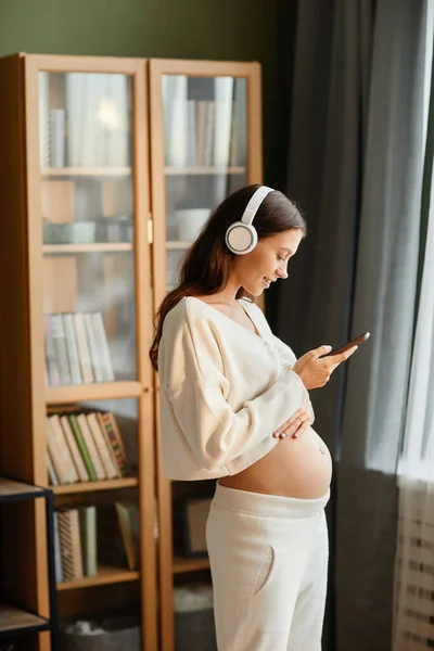Těhotná žena poslouchá hudbu s mobilním telefonem — Stock fotografie