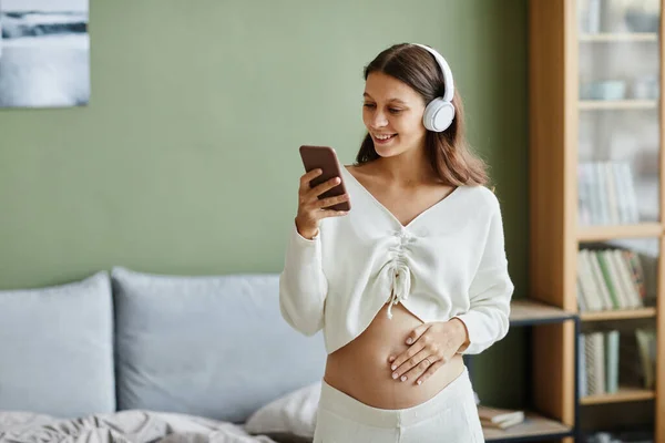 Mulher grávida curtindo a música em seu telefone — Fotografia de Stock