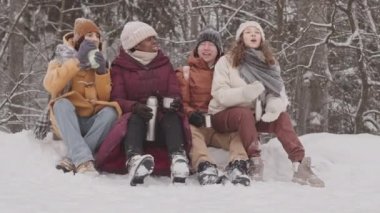 Dört farklı genç arkadaşın termodinamik bardaklardan sıcak çay içerken ve güzel kış ormanlarında karda oturup sohbet ederken yavaş çekimler.