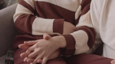 Kanepede el ele tutuşan tanınmayan bir çiftin yavaş yavaş yakınlaşması.