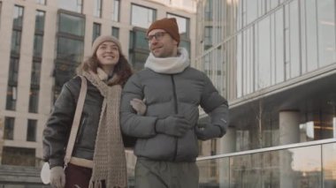 Genç beyaz çiftin sonbaharda şehir ortamında yürürken konuştuğu orta yavaş bir çekim.