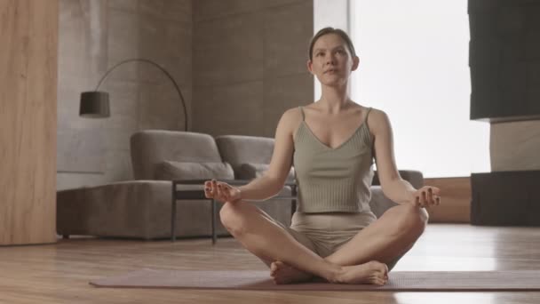 ゆっくりショットの若いです白人女性で活動的な練習ヨガ瞑想で自宅一人で — ストック動画
