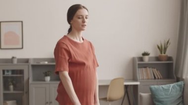 Rahat spor giyim eğitimi almış, evinde dambılları olan aktif ve genç bir kadının orta yavaş çekimi.