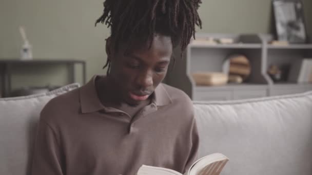 一个全神贯注的黑人年轻人坐在家里沙发上大声朗诵着 的慢镜头 — 图库视频影像