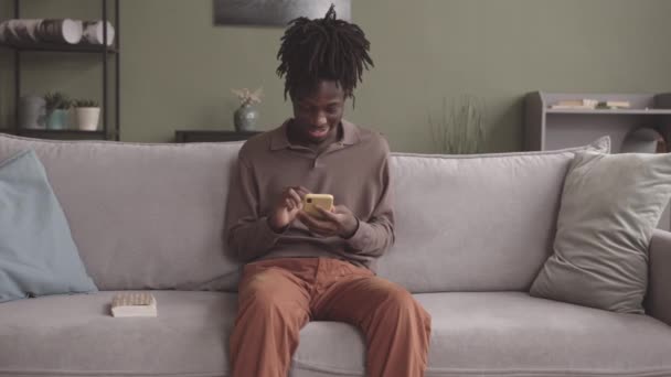 Среднестатистический Слоумокадный Снимок Молодого Афроамериканца Который Прокручивает Смартфоне Затем Берет — стоковое видео