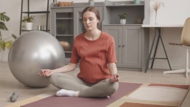 Nilüfer çiçeğinde oturan sağlıklı hamile kadının yavaş yavaş portresi meditasyon yapıyor, sonra kameraya gülümsüyor, evde yoga yapıyor.