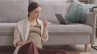 Beyaz tenli hamile bir kadının vitamin aldığı yavaş çekimler.