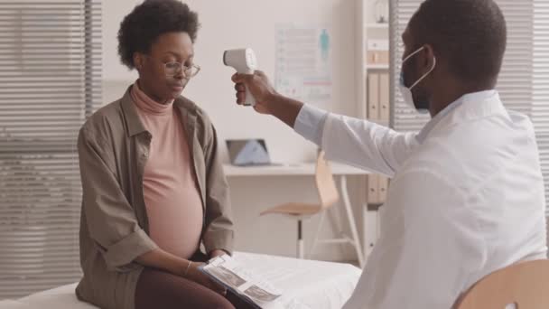 Středně Pomalý Záběr Afroamerického Lékaře Měřícího Teplotu Mladé Těhotné Ženy — Stock video