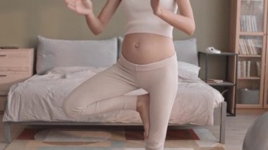 Aktif giyinmiş, yoga pozunda dua eden elleri ve gözleri kapalı duran Kafkasyalı hamile kadının yavaş çekimleri.