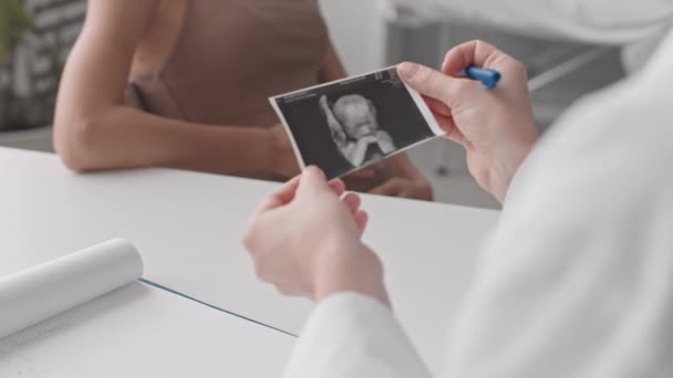 难认的女产科医生手握婴儿超声图像 在医生诊所会诊的背景下抚摩肚子的慢镜头 — 图库视频影像