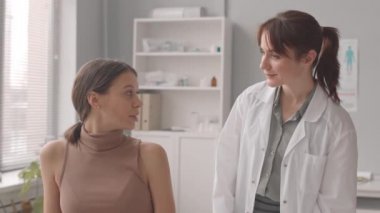 Kadın doktorun, modern klinikteki randevusu sırasında genç beyaz hamile kadının karnına dokunuşunun yavaş çekimleri.