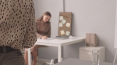 Hamile iş arkadaşına hediye veren, ofiste birlikte çalışan bir kadının yavaş çekim görüntüsü.