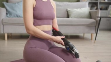 Evdeki yoga minderinde meditasyon yapan yüksek teknolojili protez kollu tanınmayan bir kadının yavaş çekimleri.