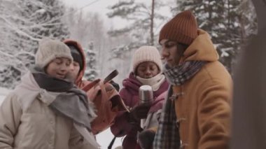 Karlı kış günlerinde araba bagajında eşyalarını toplayan bir grup genç arkadaşın orta yavaş çekimi.