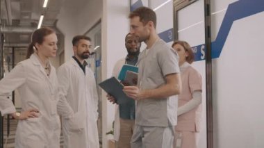 Hastane koridorunda tıp belgelerini tartışan genç doktorlardan oluşan orta ölçekli bir çekim.