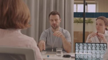 Tıbbi ekibin toplantı odasında toplanırken şişedeki aşıyı tartışırken orta ölçekli görüntüsü.