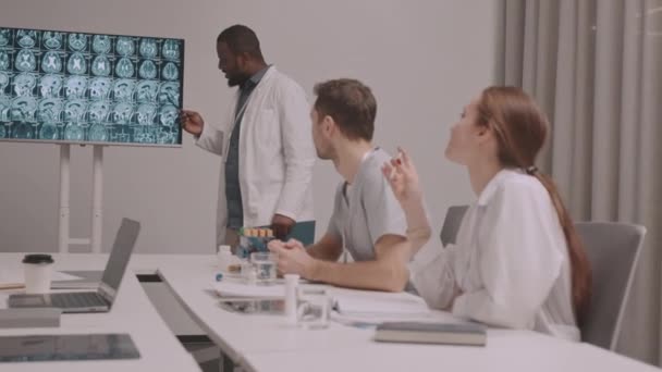 Średnie Ujęcie Afroamerykańskiego Neurologa Wskazującego Zdjęcie Rentgenowskie Mózgu Podczas Dyskusji — Wideo stockowe