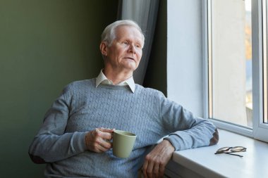 Modern son sınıf öğrencisi pencere kenarında oturup pencereden bakıyor.