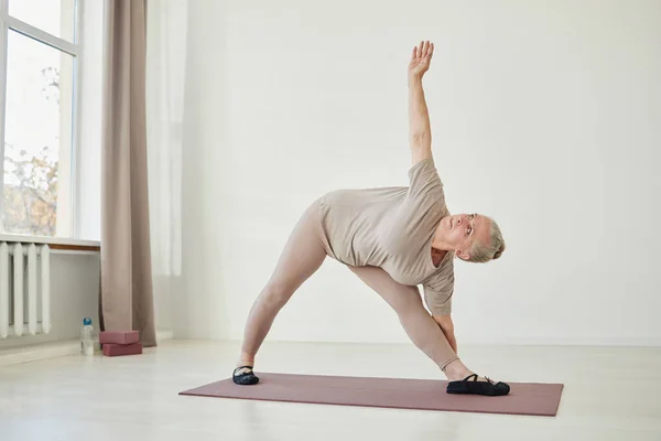 Mulher idosa ativa em roupas esportivas exercitando em casa — Fotografia de Stock
