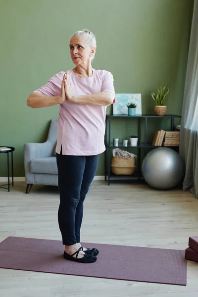 Moderna donna anziana attiva in leggins e t-shirt facendo esercizio di yoga — Foto Stock