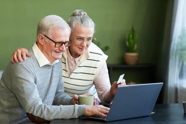 Happy senior man en vrouw op zoek naar laptop scherm tijdens online winkelen — Stockfoto