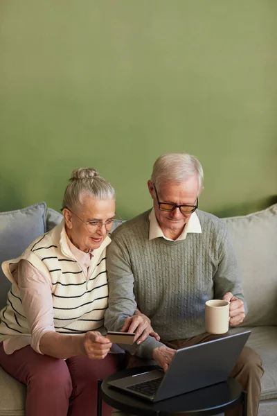 Casual senior man en vrouw zitten op de bank in de voorkant van laptop — Stockfoto