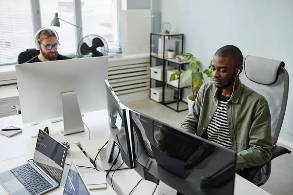 Joven programador de diversidad seria en ropa casual mirando la pantalla del ordenador — Foto de Stock