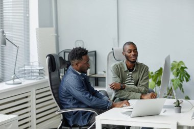 Bilgisayar monitörünün önünde oturan kendinden emin iki genç programcı.