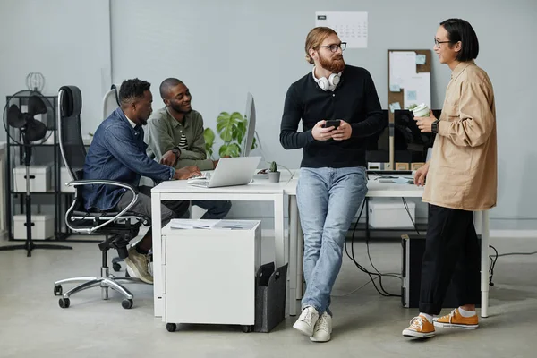 Gerentes conversando na pausa enquanto seus colegas trabalham na frente do computador — Fotografia de Stock