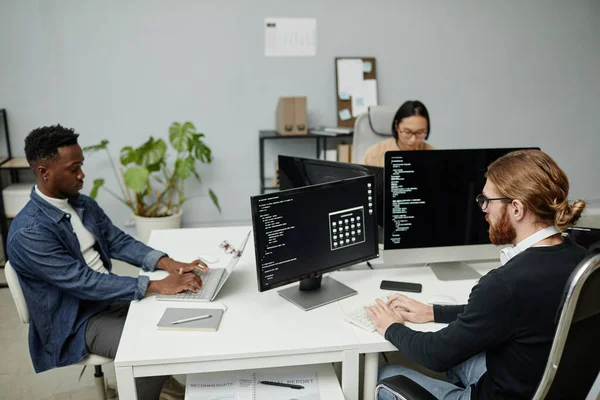 Grupo de engenheiros de software intercultural trabalhando na frente de monitores de computador — Fotografia de Stock