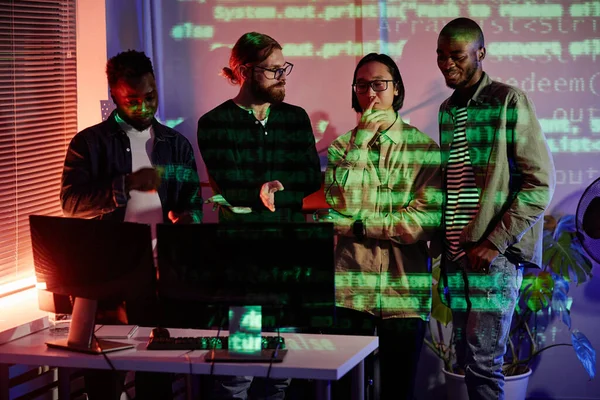Група з чотирьох інженерів-програмістів, що стоять за столом з комп'ютерним монітором — стокове фото