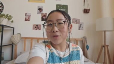 Evde video blogu kaydederken, gözlüklü ve diş telli güzel Asyalı genç kızın el kamerasıyla çekilmiş görüntüsü.