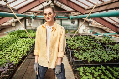 Bahçe aletleriyle büyük seranın genç ve çağdaş çalışanı.