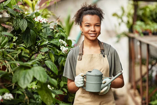 Feliz joven interracial jardinero femenino sosteniendo regadera — Foto de Stock