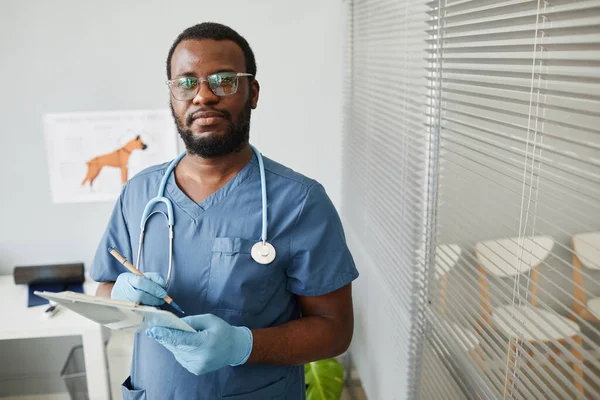 Joven veterinario afroamericano confiado haciendo notas en documento médico —  Fotos de Stock