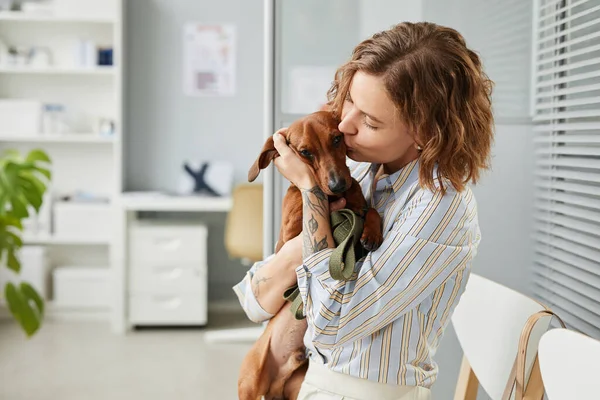 Contemporânea jovem mulher dando beijo ao seu animal de estimação bonito — Fotografia de Stock