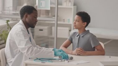 10 yaşında Afro-Amerikalı bir kızın muayenehanesine gelişinin belden aşağısı. Temassız termometresi olan genç bir Afrikalı-Amerikalı çocuk doktoru.