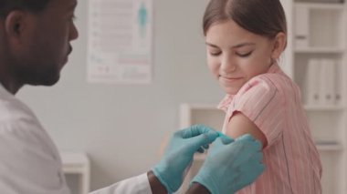 Covid-19 aşısı olduktan sonra omzuna yara bandı yapıştıran genç Afrikalı-Amerikalı doktorla konuşan 13 yaşındaki cesur kızın yavaş çekimleri.