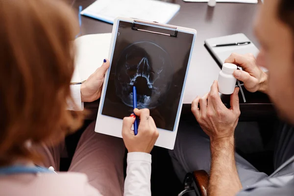 Jonge vrouwelijke radioloog wijst naar MRI scan beeld van menselijk hoofd — Stockfoto