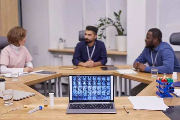 Digitalização cerebral na tela do laptop no fundo de três especialistas médicos — Fotografia de Stock