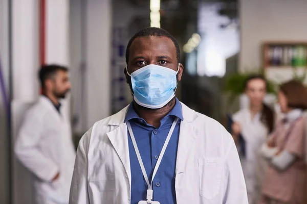 Joven médico general afroamericano en bata de laboratorio y máscara —  Fotos de Stock