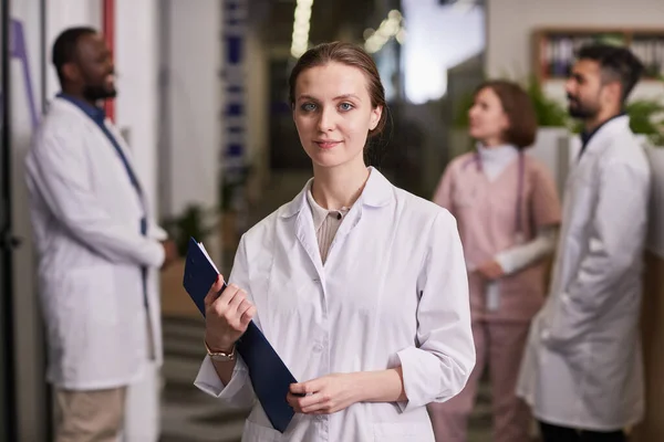 Young successful female genereal practitioner in lab coat holding document — Stock Photo, Image