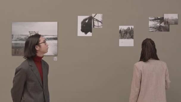 現代美術ギャラリーでの抽象的な白黒写真の展覧会を訪れる若いアジア人の中低速ショット — ストック動画