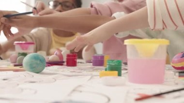 Paskalya yumurtalarını boyamak için ellerini uzatan dört farklı çocuğun paskalya tatilini birlikte geçirmek için hazırlandığı orta boy yakın çekim.