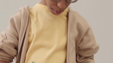 Gözlüklü Afro-Amerikan bir çocuğun orta boy portresi Paskalya yumurtalarını boyuyor sonra boyaları kameraya gösteriyor ve gülümsüyor.