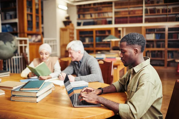 Jovem negro estudando na biblioteca — Fotografia de Stock