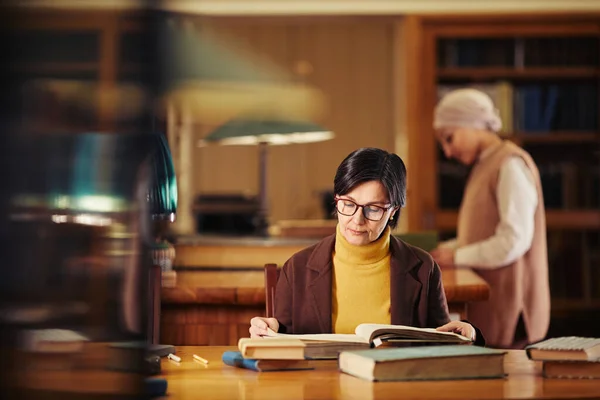 Mujer adulta leyendo en la biblioteca — Foto de Stock